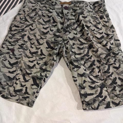 YKK RIG Utility Clothing Mens Bird Camo Cargo Shorts Grey Black Size 36 Utility

Utility cargo shorts feature a unique bird silhouette camouflage pattern in shades of grey and black. Constructed with durable cotton twill, these bottoms include multiple functional pockets with button closures and a reliable YKK zipper fly. The rugged design is finished with a branded waist patch and reinforced stitching for long-lasting wear in outdoor or casual settings.

Brand: RIG Utility Clothing
Style: Cargo Shorts
Pattern: Bird Camo
Color: Grey / Black
Material: Cotton
Waist: 36 Inches
Pockets: 6-Pocket Design
Closure: Zip Fly with Button
Fit: Relaxed
Hardware: YKK Zipper

Measurements:
• Inseam: 11.5"

Keywords: Gorpcore, Tactical, Streetwear, Avian, Hunting, Outdoor, Military, Utility, Skater, Grunge, Nature, Birdwatcher, Camouflage, Cargo, Summer

#Vintage #Outdoor #Baggy #Unisex