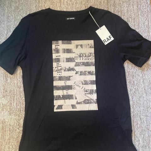 Raf Simons black t-shirt with white newspaper print graphic featuring text and images #rafsimons #newspaper

Vintage 2000s deadstock with original tags from 2007