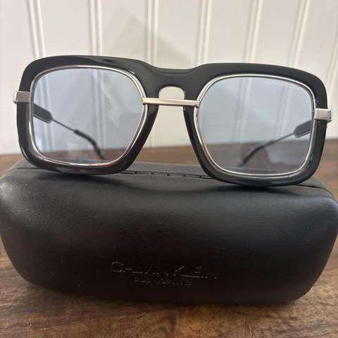 Calvin Klein 205W39NYC Raf Simons Sunglasses CKNYC1880S Square Black Blue


a rare, archival pair of Calvin Klein 205W39NYC (Model CKNYC1880S) sunglasses from the highly coveted Raf Simons design era (2017–2019). This signature unisex piece features a bold, avant-garde aviator structure constructed with a premium black acetate frame intersecting an open-space, floating silver-toned titanium inner chassis.The lenses feature a distinct, uniform light blue aesthetic tint. This model is completely discontinued, sold out globally, and highly sought after by collectors of modern American fashion history.Condition & DetailsCondition: Excellent, gently used pre-owned condition. The frame chassis is structurally perfect, hinges are crisp and tight, and the acetate holds its deep, original high-gloss luster.Lenses: Excellent condition with minimal to no visible wear. Clear vision.Inclusions: Includes the original, authentic black debossed Calvin Klein 205W39NYC protective hard case