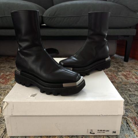 Peter Do Metal Tip Combat Boots in black / silver, size 36 (fits women's US size 6). Originally $1495.
Smooth napa leather moto booties. 2" block heel with metallic accent. Square metal tip toe and metal heel bumpers. Medial side zip eases dress. Stacked leather midsole with lugged Vibram rubber sole.  Black leather lining. Made in Italy.
In excellent preowned condition; minor scuffing throughout and one zipper pull was replaced. Comes with original box (large box; can ship without if cheaper shipping cost desired).
Some on foot pics are of the glossier leather model; the one for sale is the low gloss leather model.